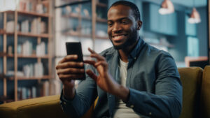 Excited,Black,African,American,Man,Using,Smartphone,While,Resting,On